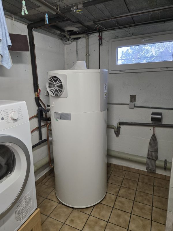Chauffe-eau thermodynamique installé dans une buanderie avec son espace d’accès et ses raccordements