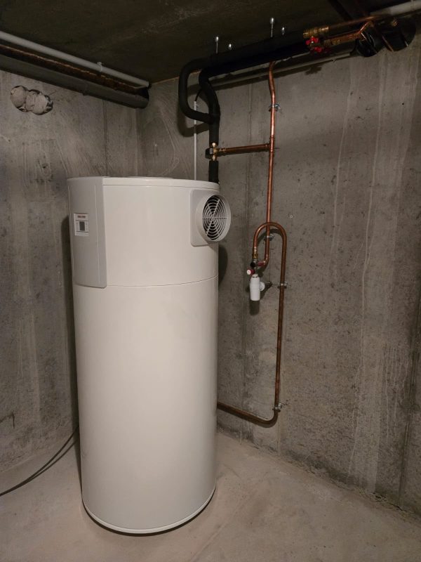 Chauffe-eau thermodynamique installé dans un sous-sol avec ses raccordements apparents
