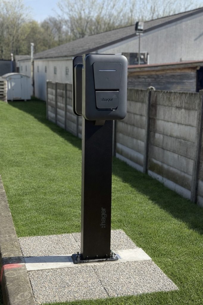 Borne de recharge Hager installée sur un pied extérieur fixé sur un socle en béton.